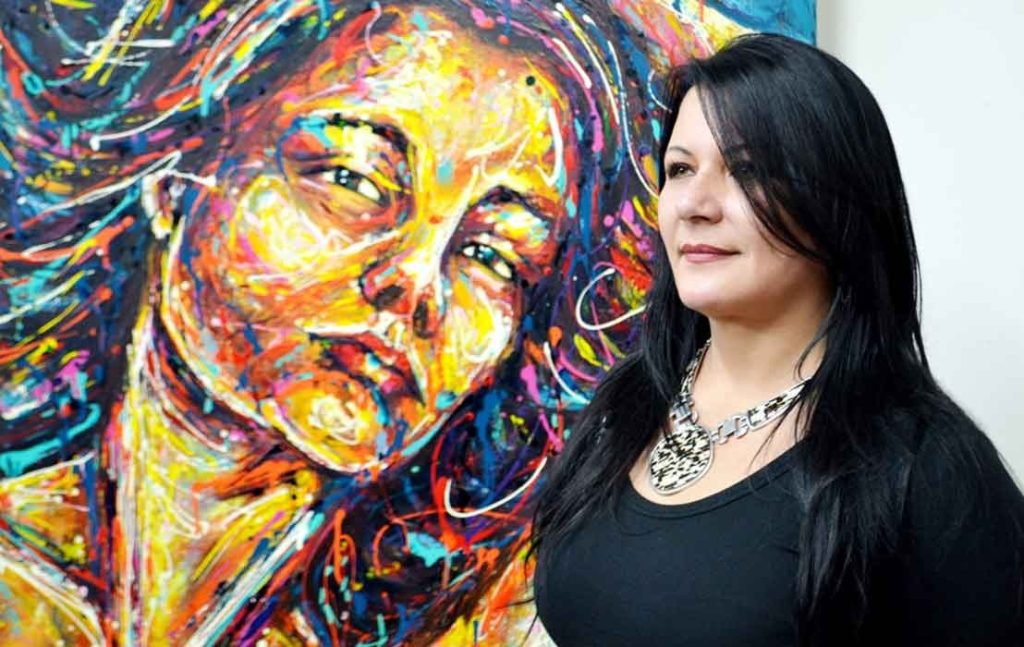 Exposiciones de Arte Diana Francia con una obra de arte de su autoria al fondo